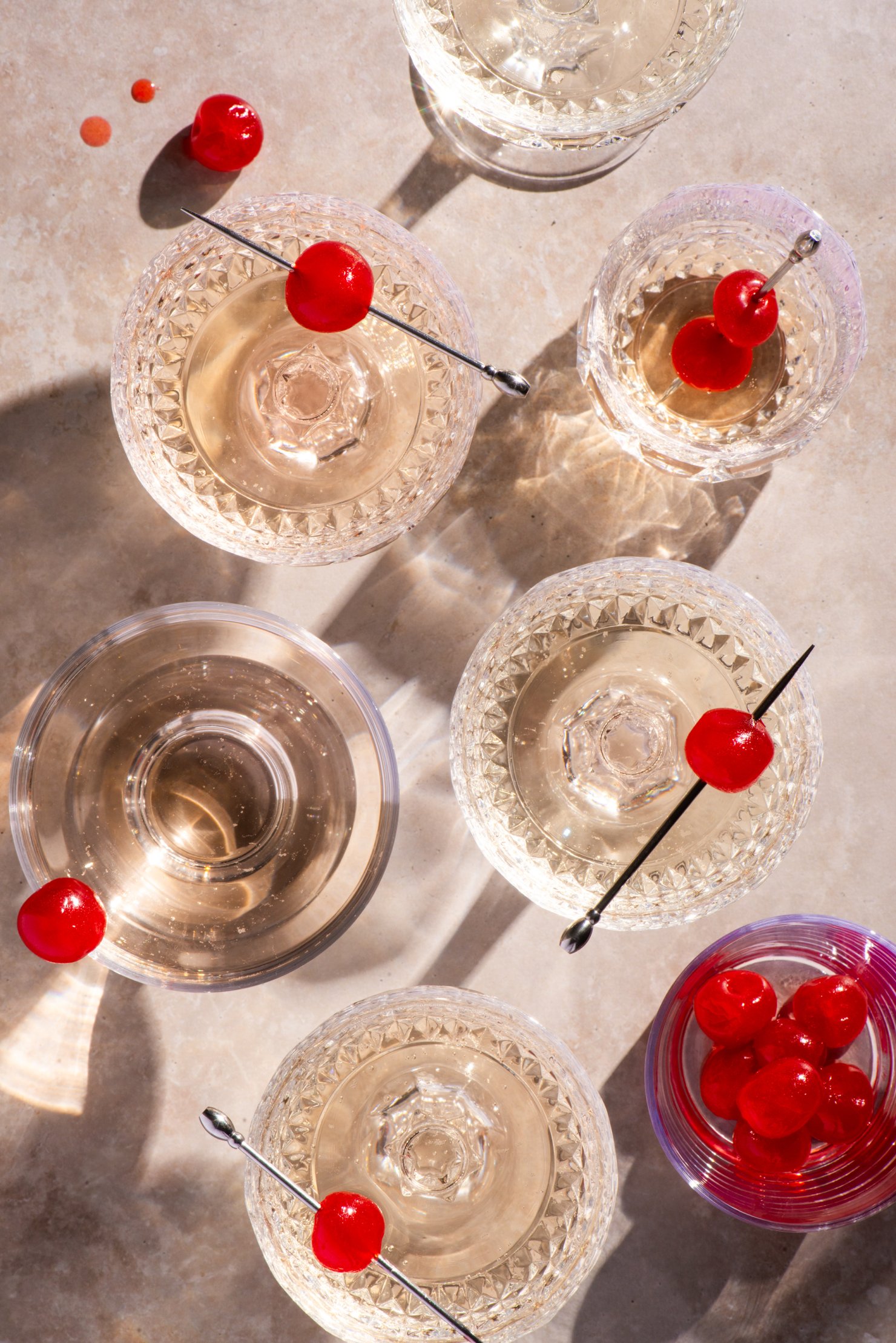 Playful image of champagne in vintages glasses with cherries arranged in geometric fashion
