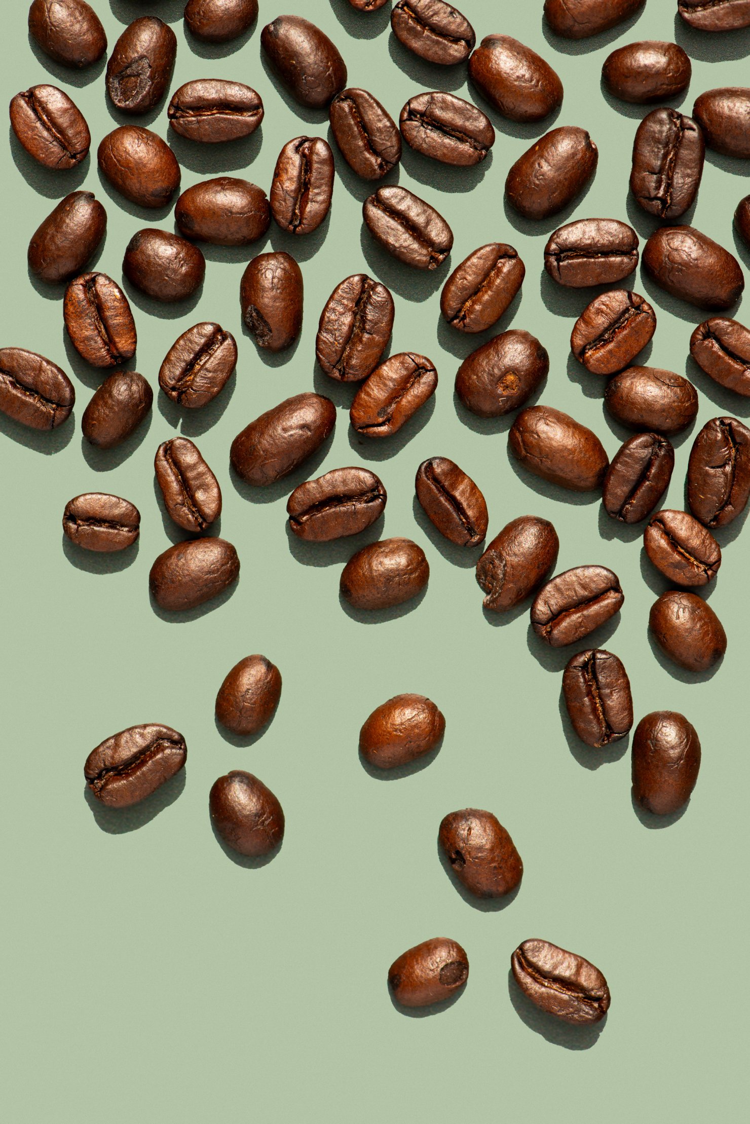 Close up of coffee beans playfully placed on green background