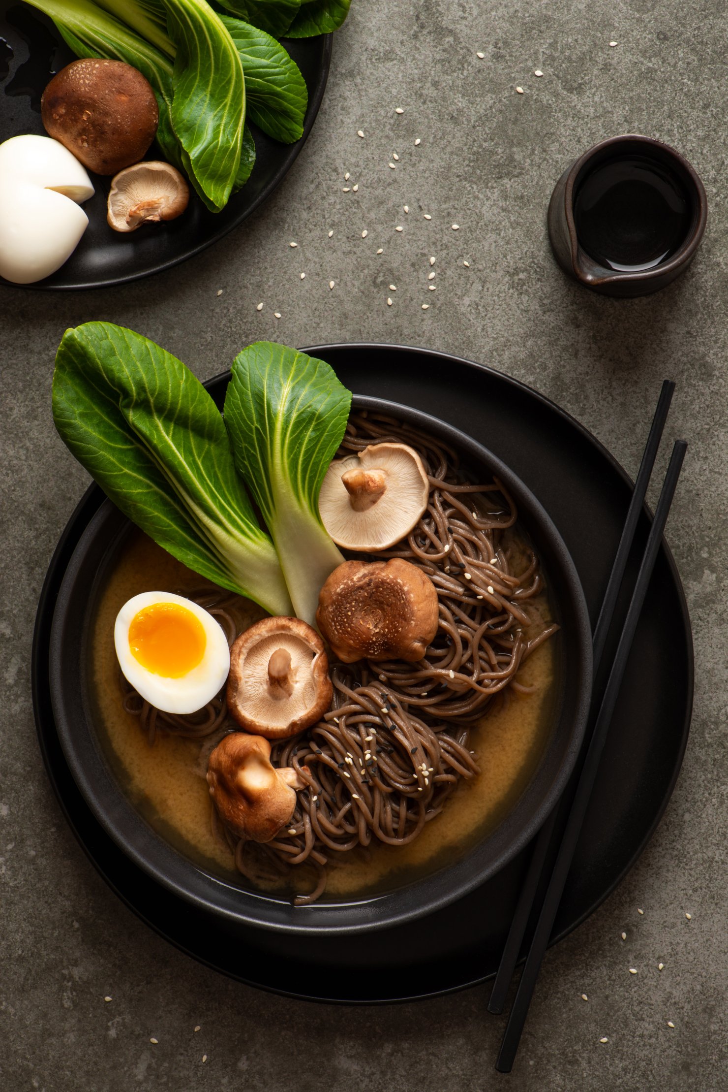 Food photography image of bowl of soba noodles in miso broth with shiitake mushrooms, bok choy and soft boiled egg