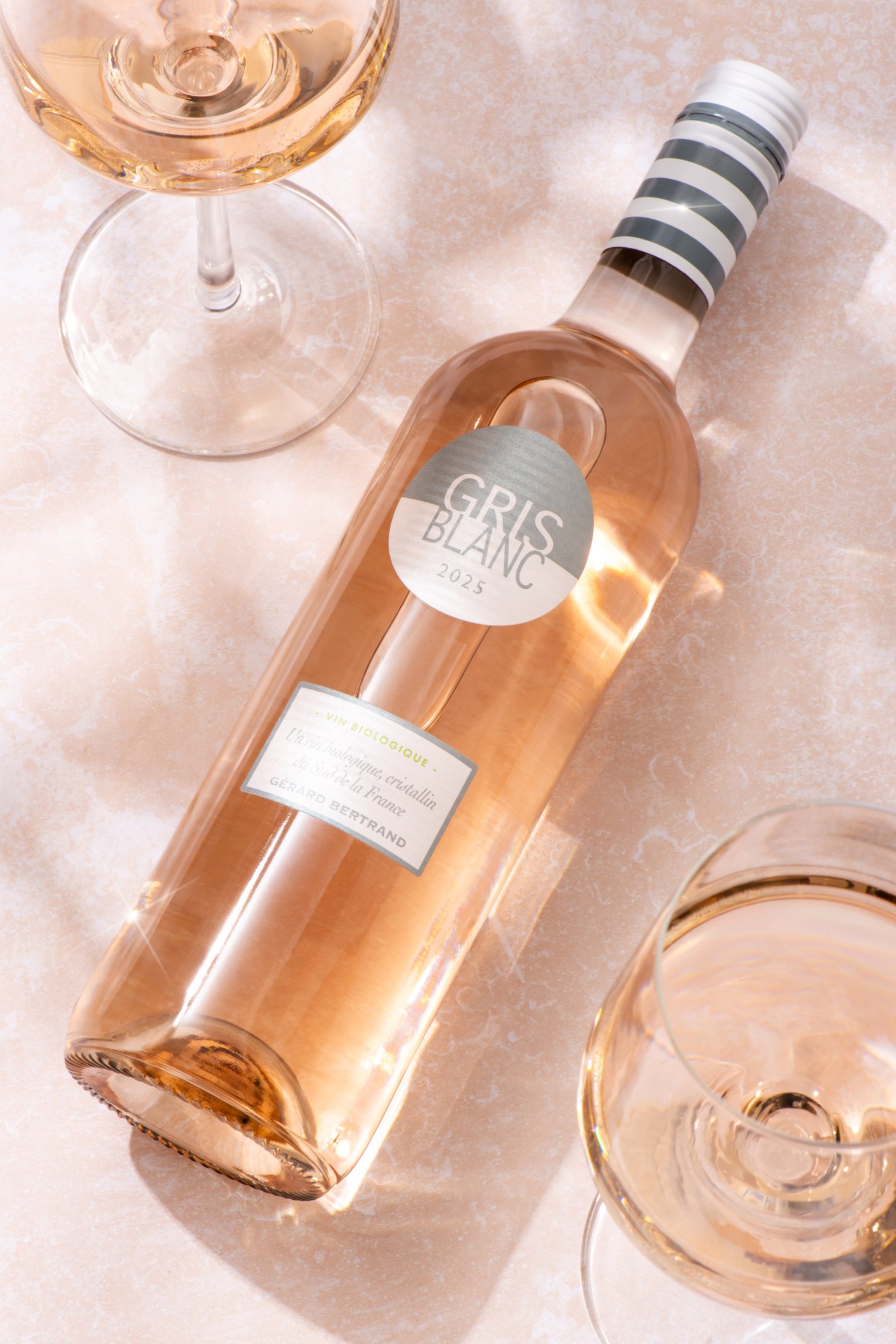 Flat lay product photography image of rosé wine bottle on sunny pink stone background