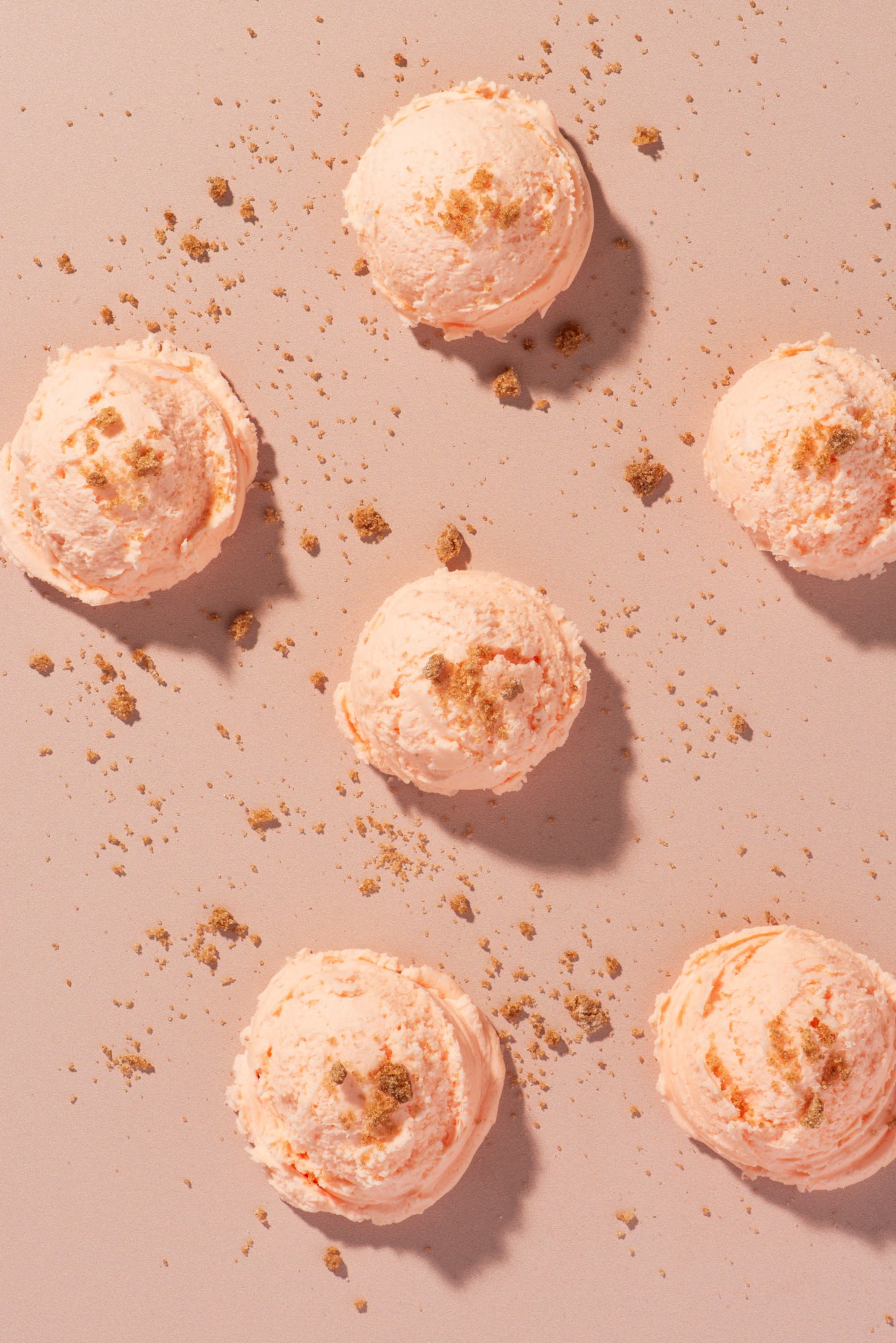 Six scoops of peach ice cream sprinkled with brown sugar in monochromatic top view