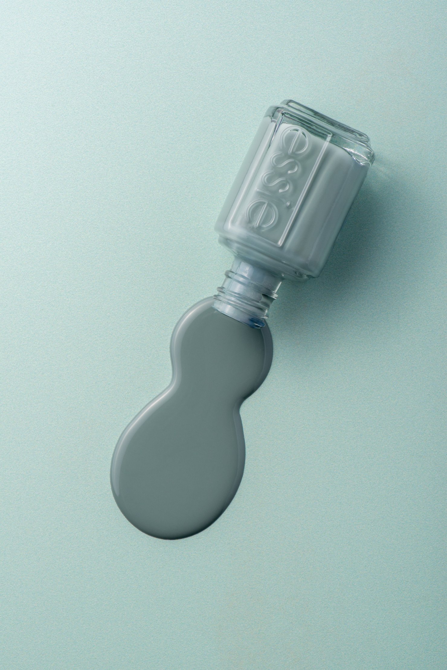 Teal essie nail polish spilled on background of same colour, product photography by Mel Discepola