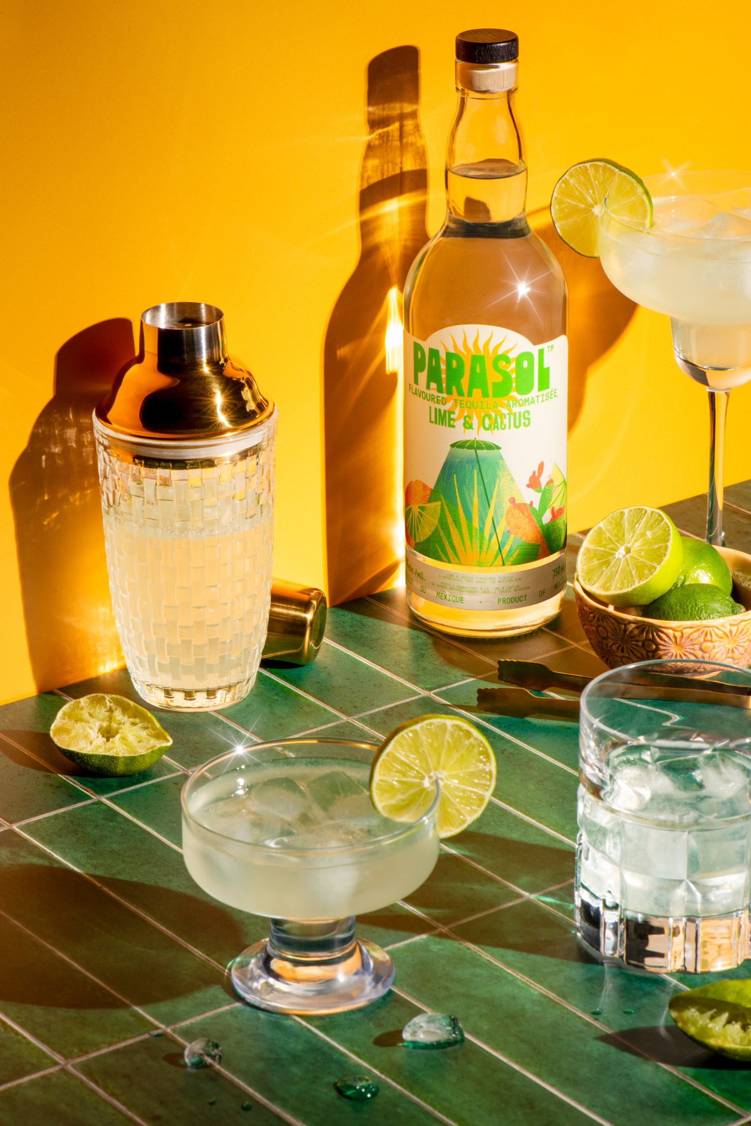 Hard light commercial photography of Bottle of Parasol Flavoured Tequila in sunny setting with margarita drinks
