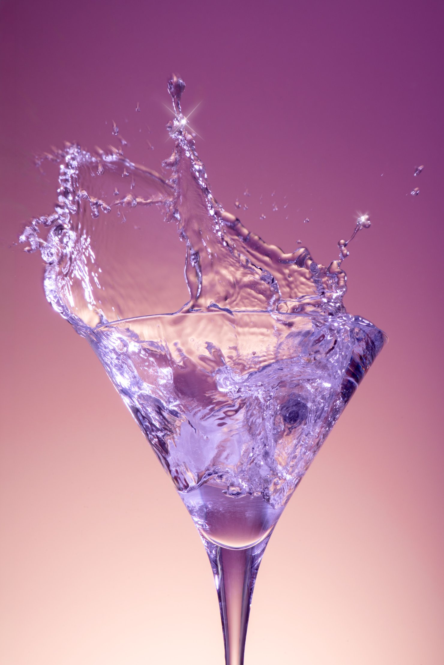 Commercial photography of martini glass frozen mid splash with pink and purple hues