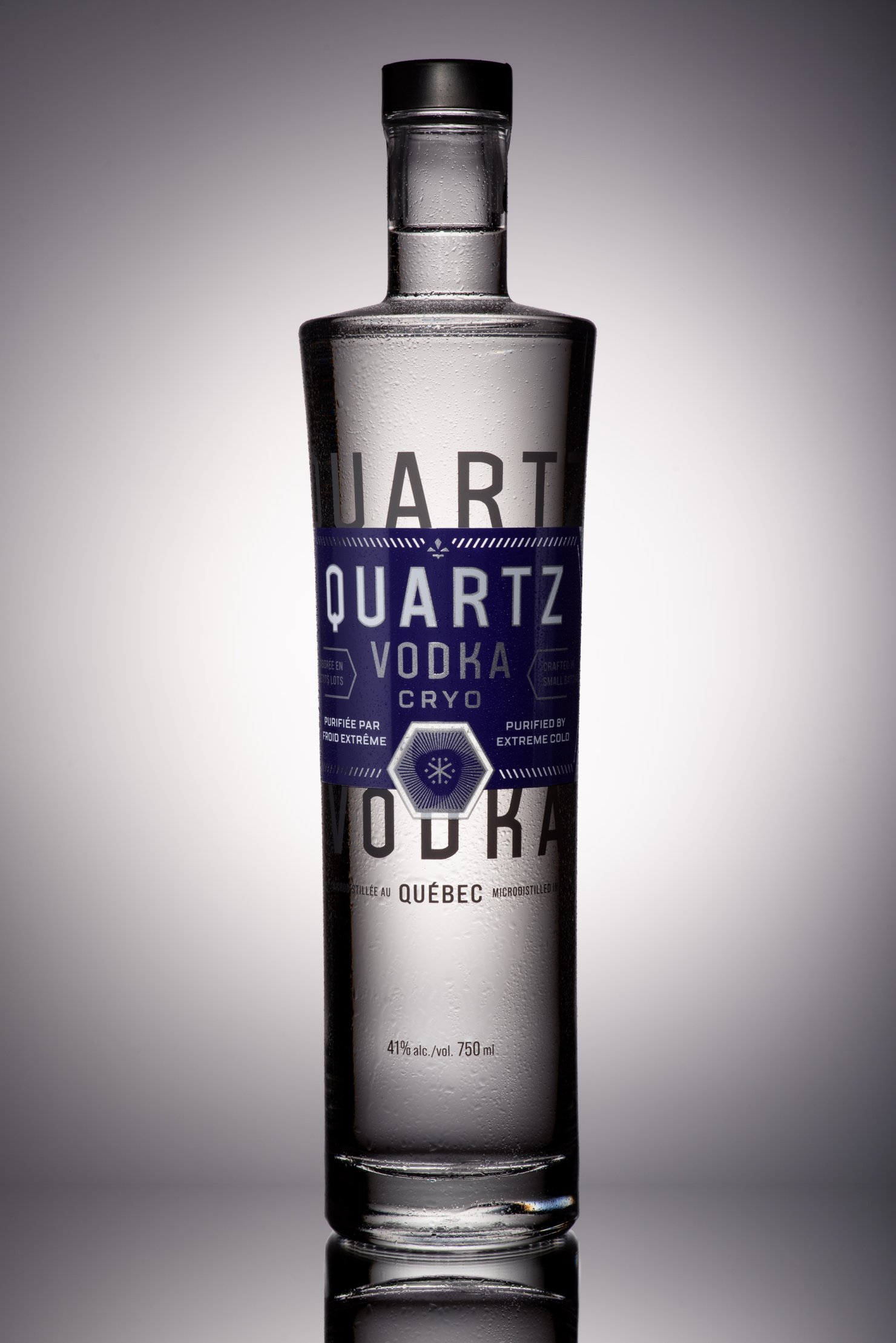 Dramatic product photo of Quartz vodka bottle, back lit on reflective surface