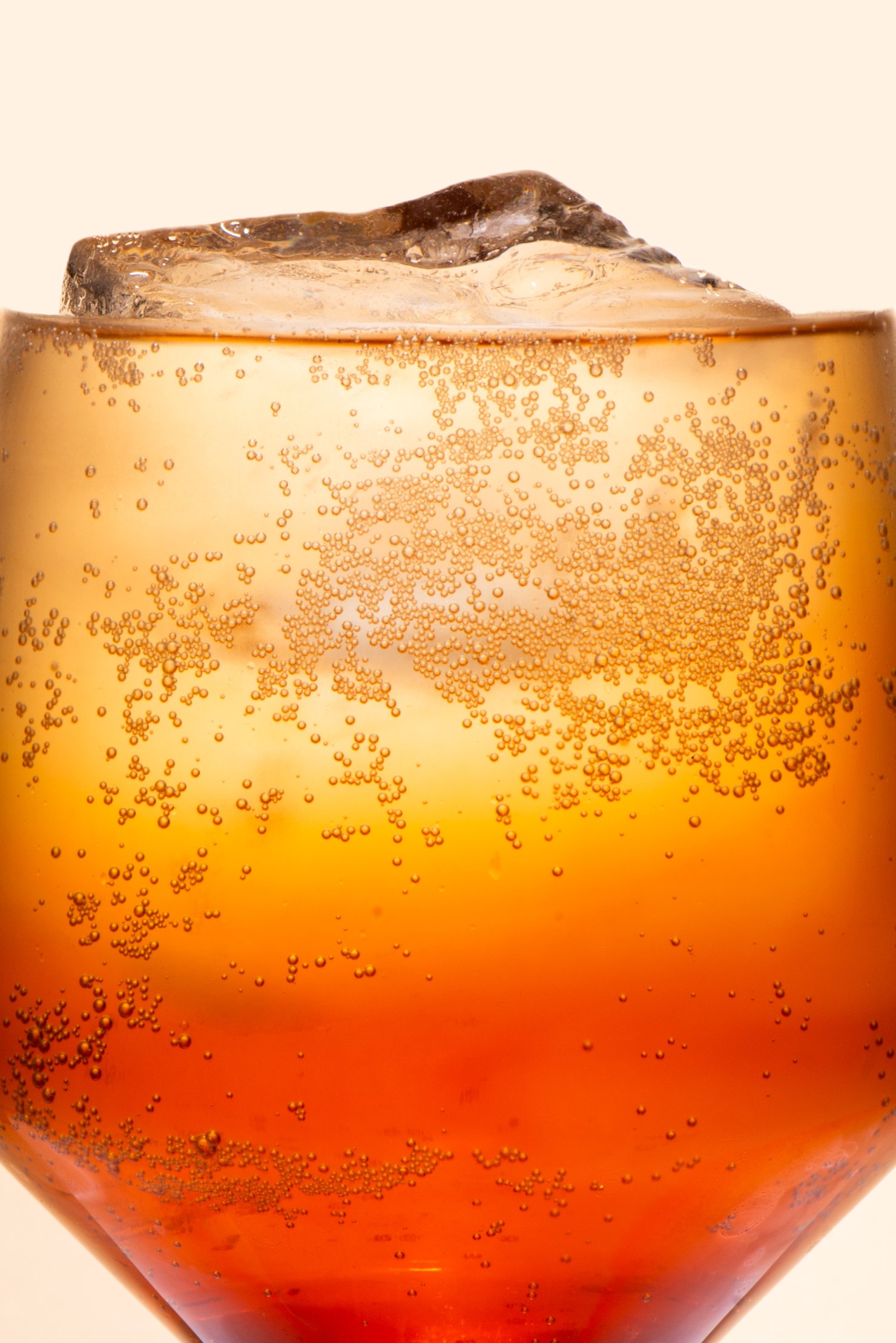 Close up of orange and yellow drink with clear ice and bubbles