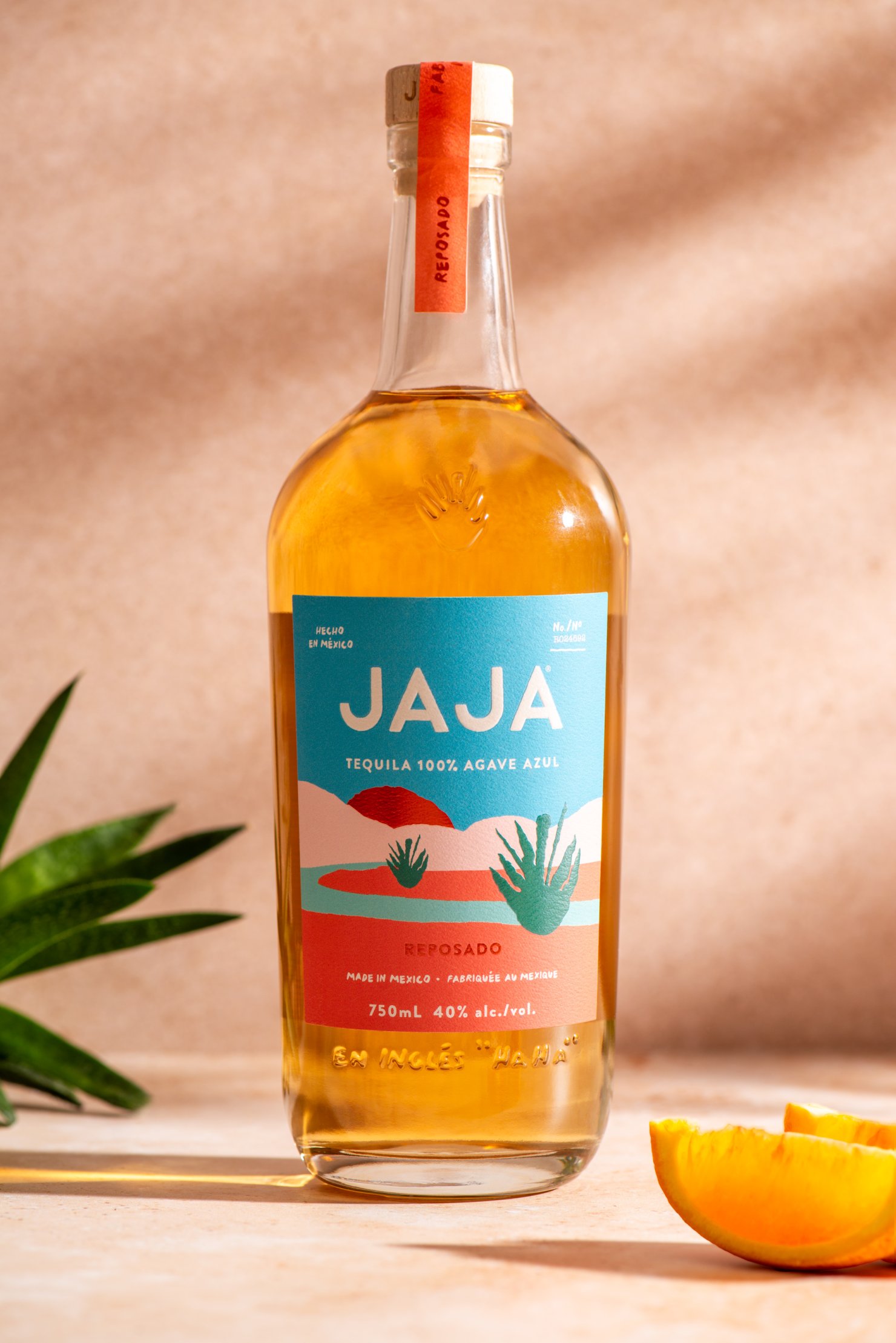 Product photography image of Jaja Tequilla bottle in warm setting with plant and blood orange slices