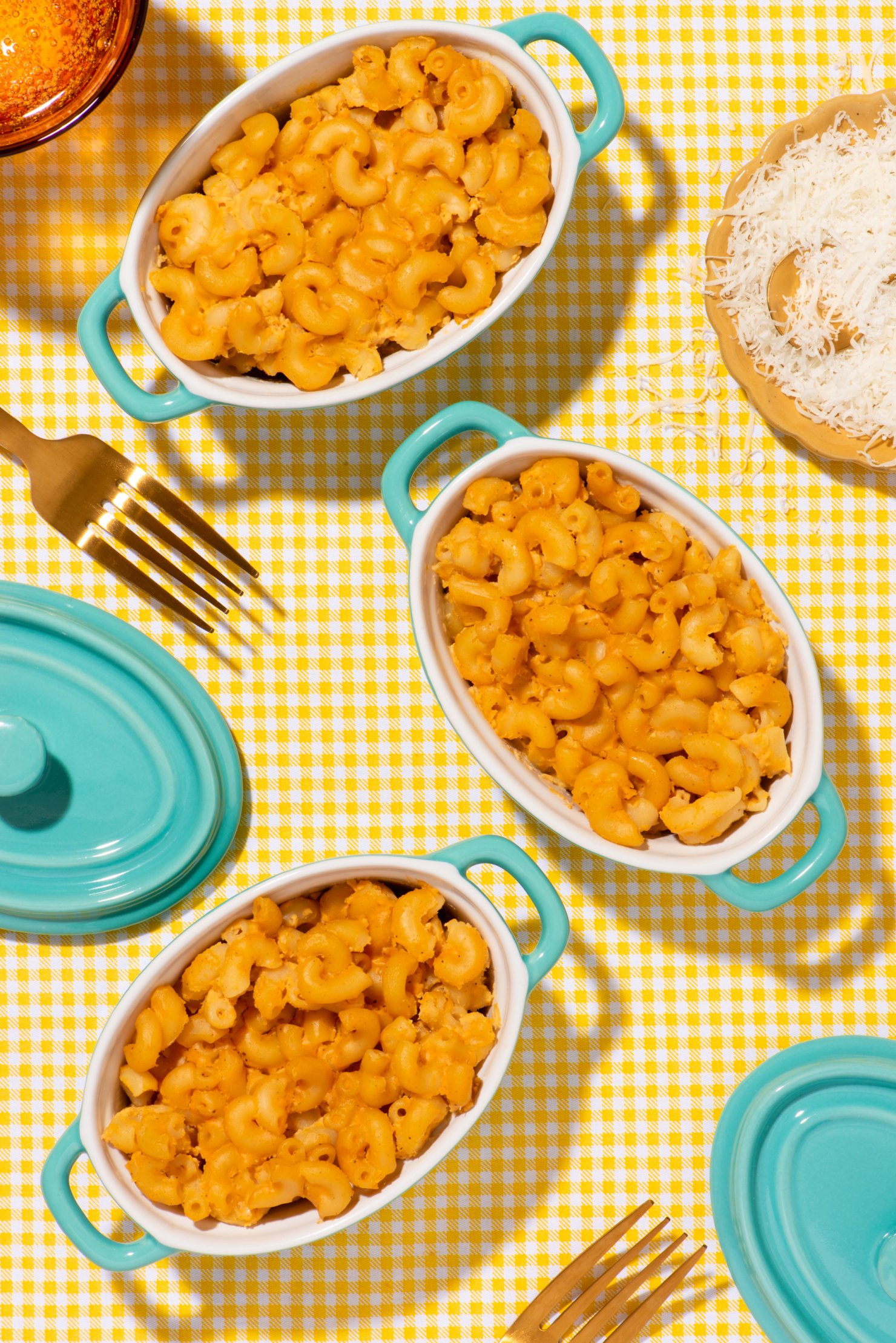 Contemporary food photography of turquoise bowls of vegan macaroni and cheese on yellow checkered linen